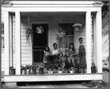 T. J. Martin, miner, and family on front porch of their home. Mr. Martin came here 13 months ago. Has saved enough... - NARA - 540982