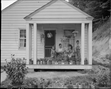 T. J. Martin, miner, and family on front porch of their home. Mr. Martin came here 13 months ago. Has saved enough... - NARA - 540980