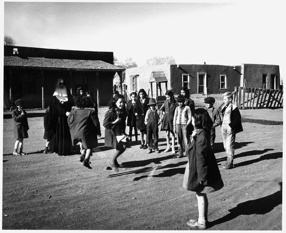 Taos County, New Mexico. A Catholic Sister, teacher in the Costilla school, helps swing the rope fo . . . - NARA - 521985