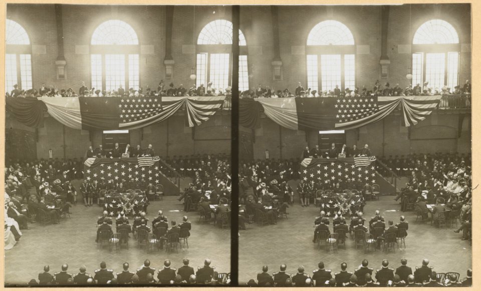 Teddy Roosevelt on a flag-draped platform, speaking to a group of people LCCN2009633761
