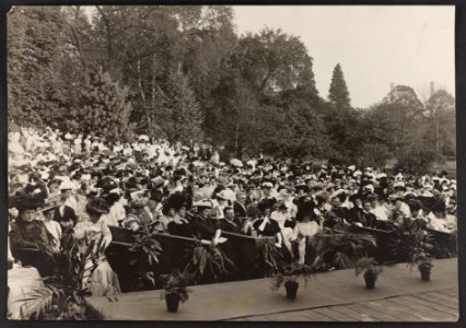 Teddy Roosevelt seated in an outdoor stage box, surrounded by other audience members LCCN2009633762