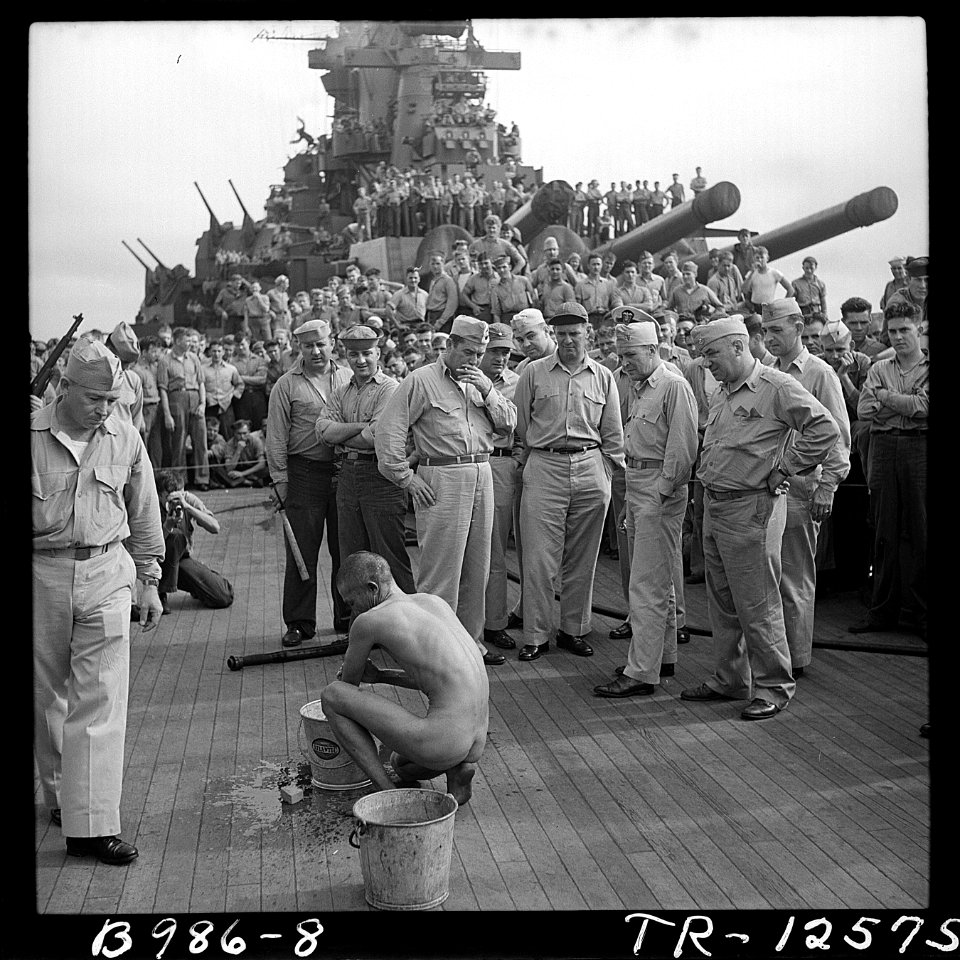 The crewmen of the battleship USS New Jersey watch a Japanese prisoner of war bathe himself before he is issued GI... - NARA - 520874