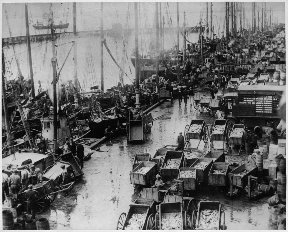 The rain-swept Boston Fish Pier, crowded with fish carts, fishing boats, and workmen, ca. 1950 - NARA - 541953
