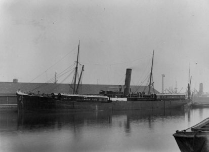 The SS Africa in dock with four railway carriages loaded onto the vessel, two fore and two aft