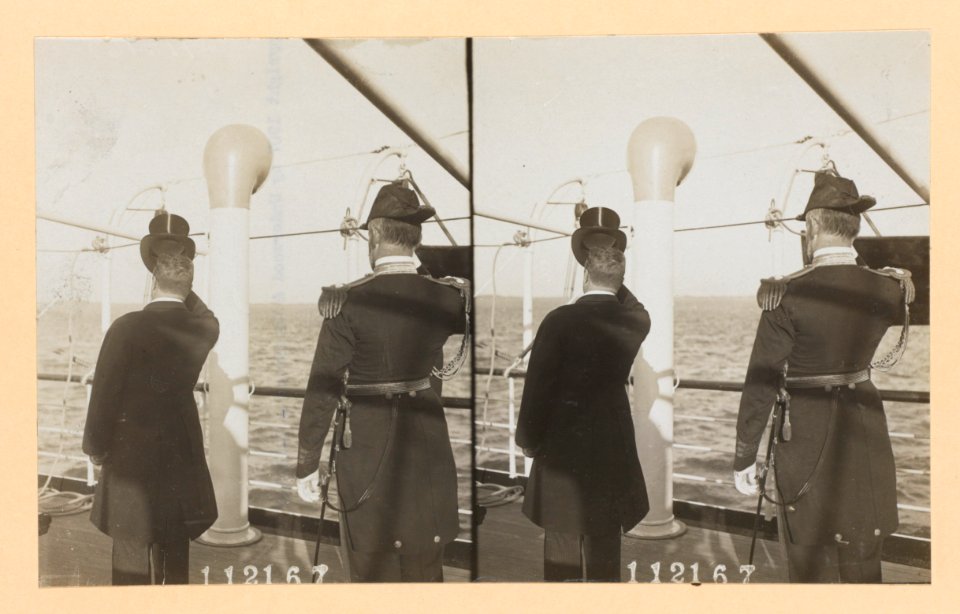 Theodore Roosevelt and a naval officer on deck of ship, their backs to camera, Roosevelt tips his hat LCCN2013650576