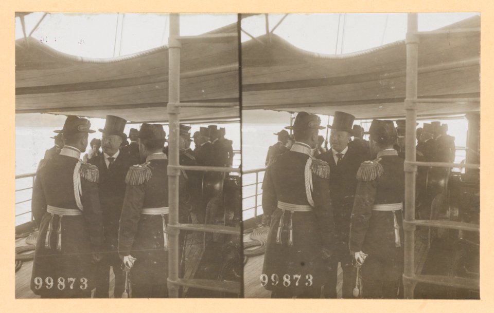 Theodore Roosevelt conversing with two naval officers on deck of ship. Group of people in the background LCCN2013650577