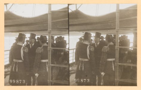 Theodore Roosevelt conversing with two naval officers on deck of ship. Group of people in the background LCCN2013650577