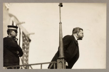 Theodore Roosevelt speaking on a raised platform, leaning forward toward the audience LCCN2009633782