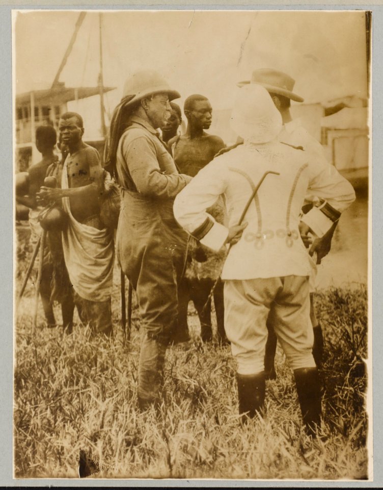 Theodore Roosevelt standing with mostly African men in traditional dress LCCN2010645481