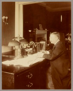 Theodore Roosevelt, full-length portrait, seated at his desk writing LCCN2013649624