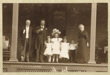Theodore Roosevelt, full-length portrait, standing on porch, facing front, holding cup and saucer, with older man, older woman, and four children LCCN89709271