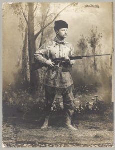 Theodore Roosevelt, full-length portrait, standing, facing right, in deer skin hunting suit, holding rifle LCCN2009633164