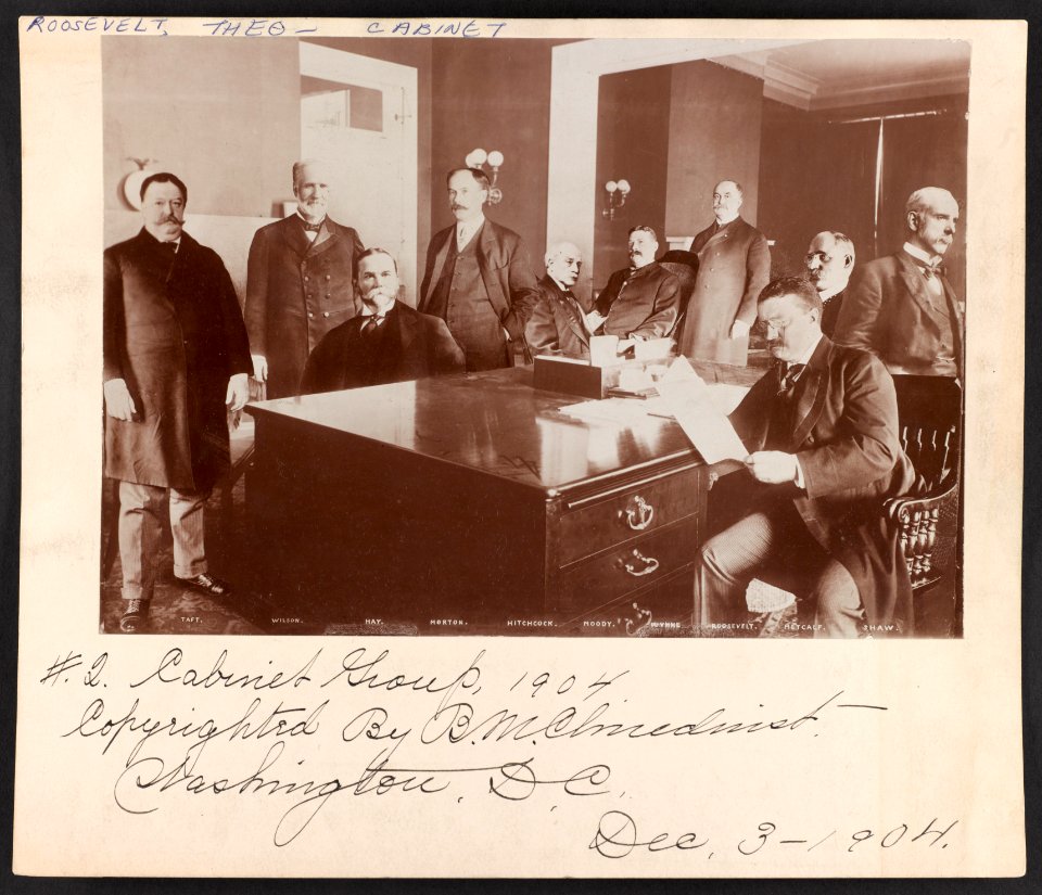 Theodore Roosevelt, seated at desk reading, surrounded by cabinet members LCCN2013649638