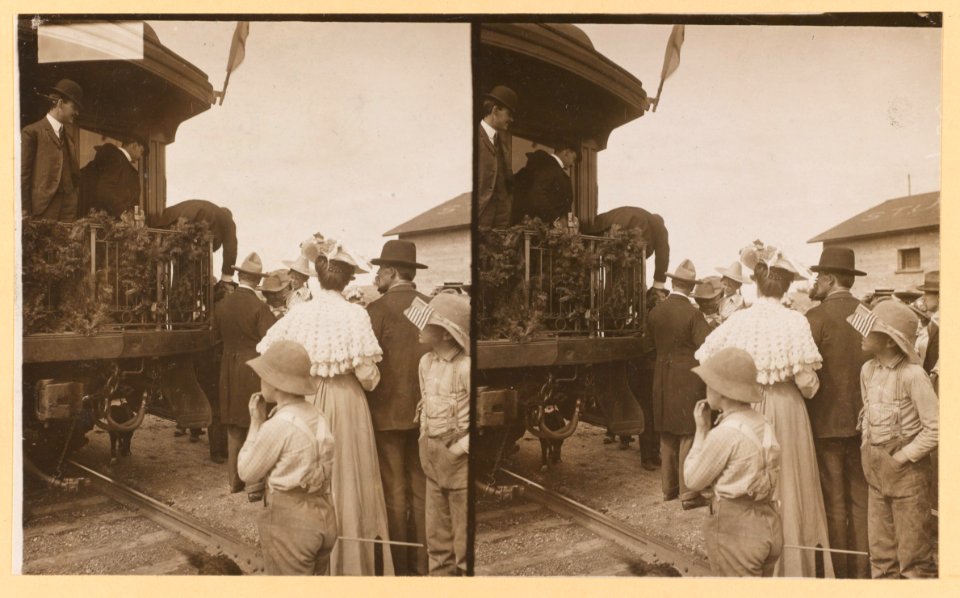 Theodore Roosevelt, leaning over the rear platform of railroad car to shake hands) LCCN2009633752