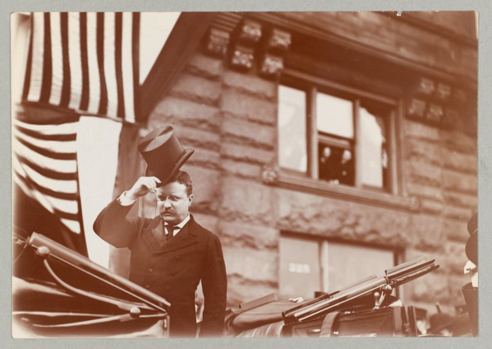 Theodore Roosevelt, standing in open carriage, tipping his hat LCCN2007680994