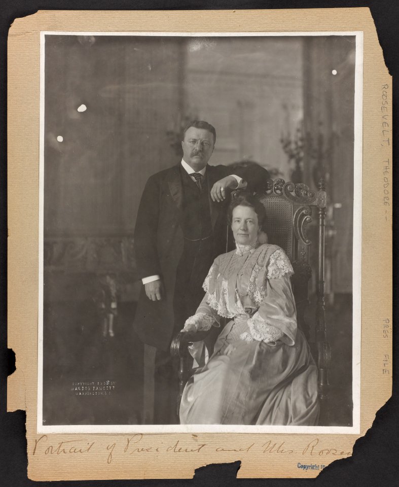 Theodore Roosevelt, three-quarter length portrait, standing, facing right; alongside his wife, seated LCCN89707303