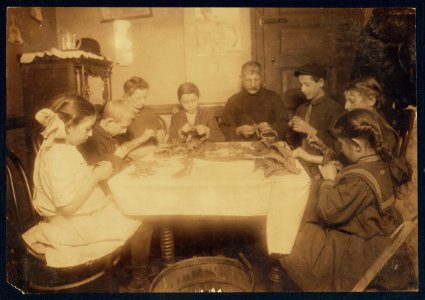 These garters are made for Berger, 92 Spring St. 9-00 P.M., Feb. 27-12. Making garters (armlets). A Jewish family and neighbors working until late at night. This happens several nights in the week when there is LOC nclc.04202 photo