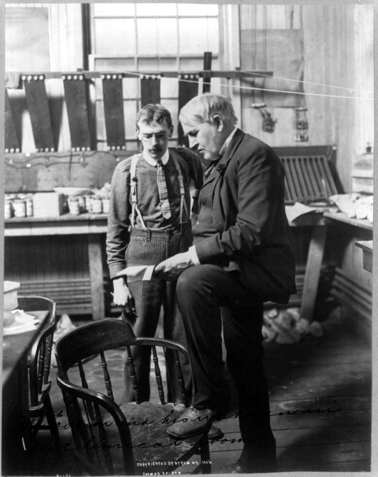 Thomas Alva Edison, 1847-1931, full-length portrait, standing, facing left, with his workman in the chemical room LCCN2005685790