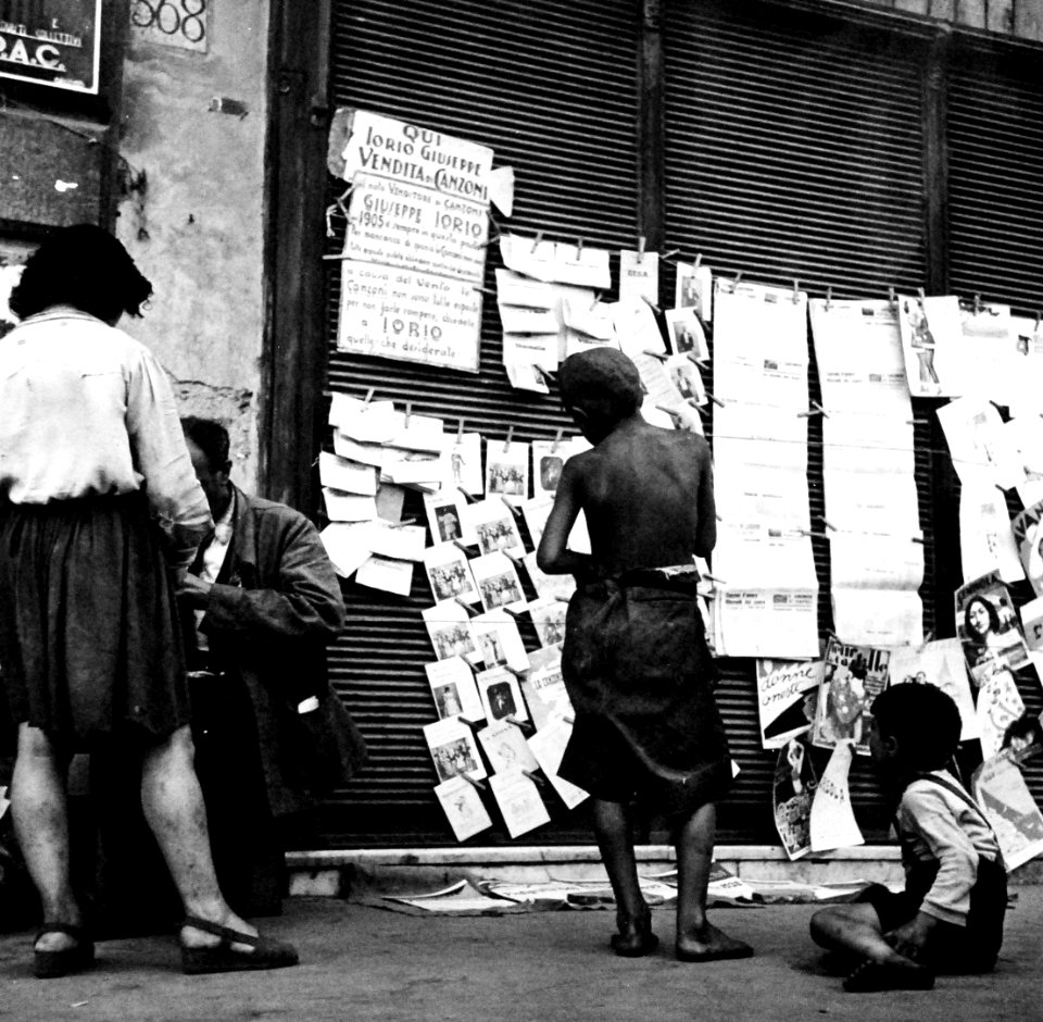 “Children In Naples, Italy”. Boys and newspapers. Photographed by Lieutenant Wayne Miller, July 1944. U.S. Navy Photograph, now in the collections of the National Archives
