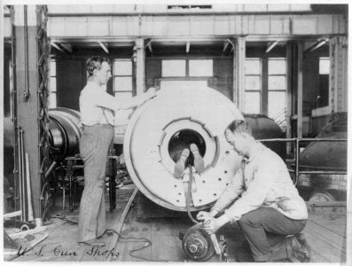 Three men working on large gun in Naval Gun Factory, Washington, D.C.; one of the men lying in the barrel LCCN2004668412