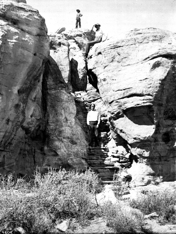 Three men climbing the foot trail to the top of the mesa of the Hopi (Moki) pueblo of Mishongnovi (Mashongnave), Arizona, ca.1898 (CHS-4604)