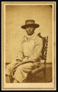 Three-quarter-length portrait of an African American man seated facing front, wearing hat and bandana LCCN2010647829