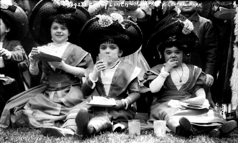 Three women with dwarfism at party in Central Park in May 1900, Midgets eating lunch - May party - Central Park. Three midgets sitting on the grass. LCCN2014688122 (cropped)