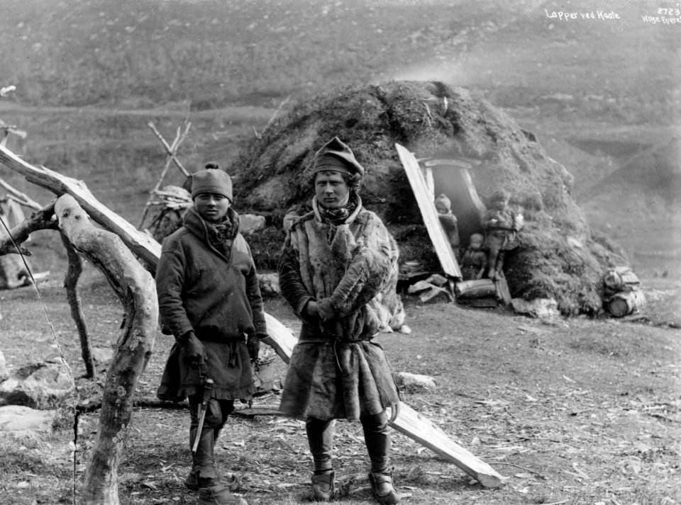 To svenske samer fra Karesuando foran en gamme, tre barn i døråpningen. Antagelig Tromsdalen ca - Norsk folkemuseum - NF.06789-022