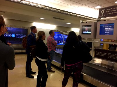 Travelers watch presidential debate on monitors at Ronald Reagan Washington National Airport baggage claim