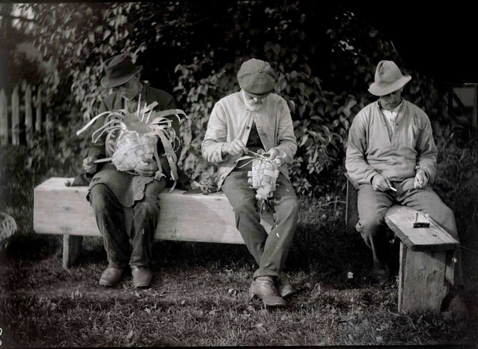 Tre män på bänk tvinnar metrev och flätar näverkorg. Jösse härad, Mangskogs socken, Värmland - Nordiska Museet - NMA.0036533