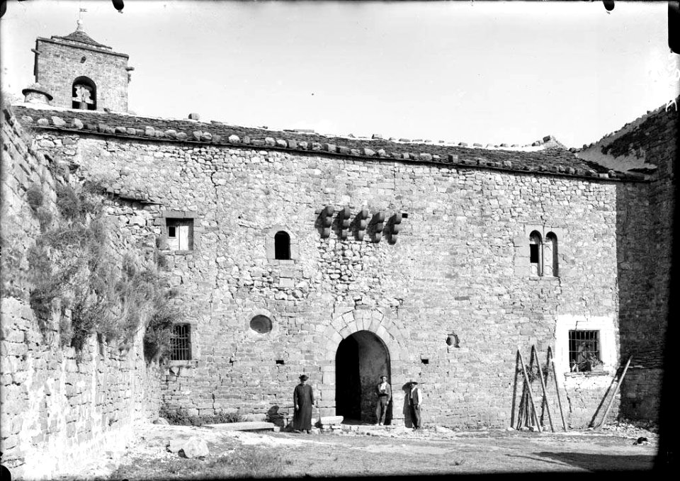 Tres homes, un d'ells sacerdot, davant del monestir de San Victorián