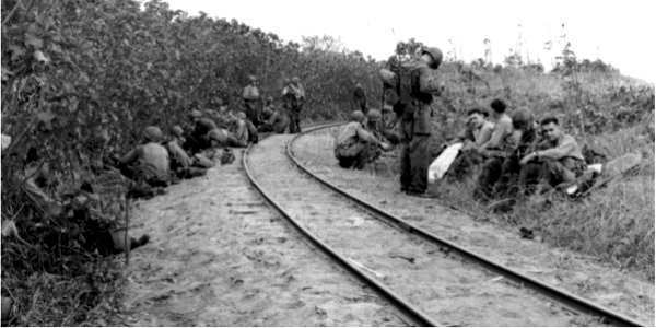 Troops resting beside the narrow gauge Japanese railroad on Saipan