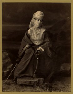 Turkish woman, full-length portrait, seated, facing front, holding parasol and flowers LCCN2003677089