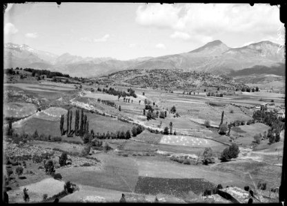 Turons amb camps i alguns arbres i muntanyes al fons, des de San Feliú de Veri