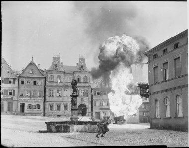 Two anti-tank Infantrymen of the 101st Infantry Regiment, dash past a blazing German gasoline trailer in square of... - NARA - 531289