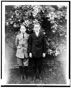 Two boys posed, standing in front of wall and blooming tree LCCN93502903