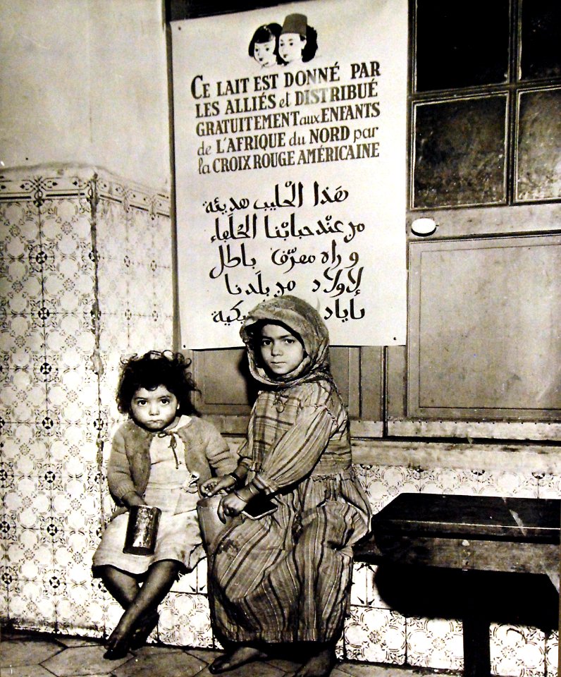 Two Arabian children have just received their daily milk ration, Algeria, 1943 (27325808250)