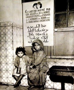 Two Arabian children have just received their daily milk ration, Algeria, 1943 (27325808250)