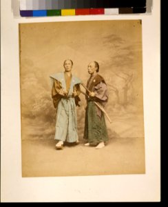 Two Japanese men, possibly samurai, full-length studio portrait with backdrop, standing, one facing front and the other facing left, each with two swords LCCN2009632870