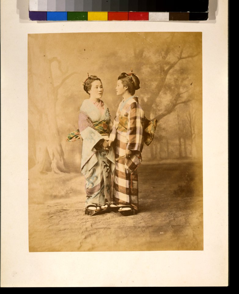 Two Japanese women, full-length studio portrait with backdrop, standing, facing each other, holding hands LCCN2009632871