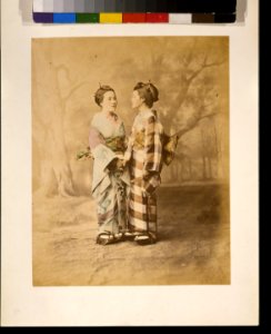 Two Japanese women, full-length studio portrait with backdrop, standing, facing each other, holding hands LCCN2009632871