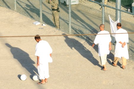 Two detainees walk around and another gets ready to kick a soccer ball within the outdoor recreation area of Camp Six at Joint Task Force Guantanamo DVIDS373569 photo