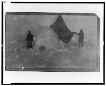 Two members of Frederick Cook's expedition, with U.S. flag stuck in igloo, at expedition camp site, North Pole LCCN2001695579