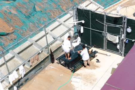 Two detainees wash a mat in the outdoor recreation area of Camp Six at Joint Task Force Guantanamo DVIDS380256
