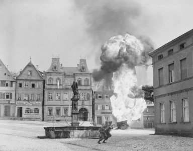 Two anti-tank Infantrymen of the 101st Infantry Regiment, dash past a blazing German gasoline trailer in square of... - NARA - 531289 Croped, stants deleted