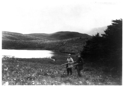 Two men with guns in foreground, pond and mountain in background, taken during the Harriman Alaska Expedition, 1899 LCCN92513833