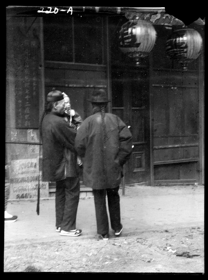 Two men, one holding a child, standing in the street, Chinatown, San Francisco LOC agc.7a09082