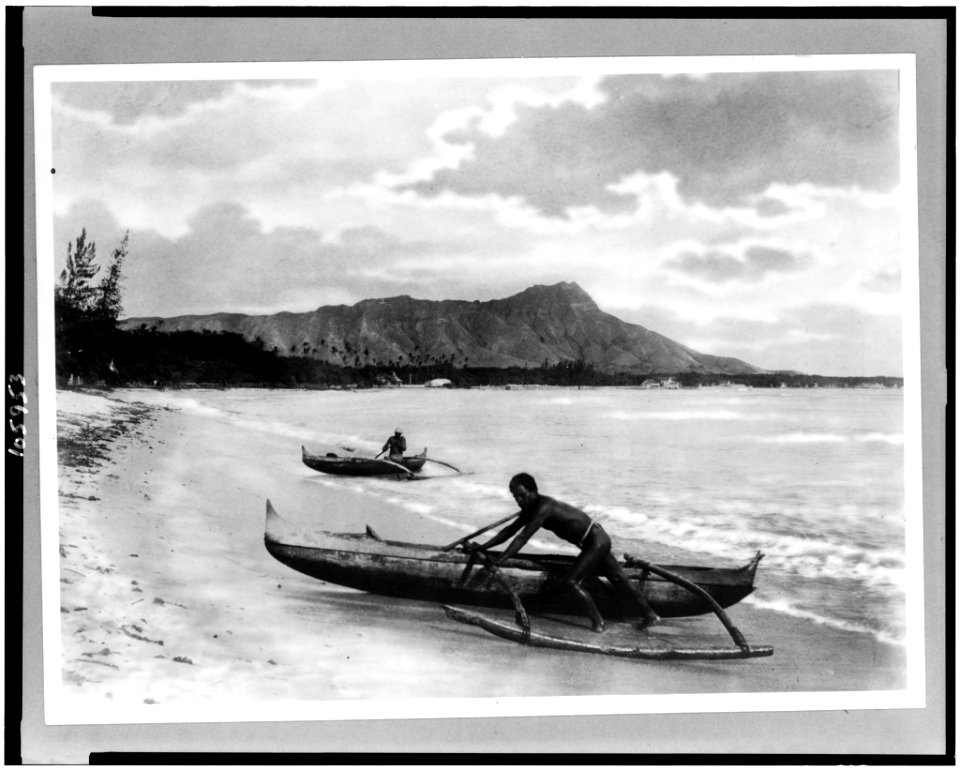 Two natives with outrigger canoes at shoreline, Honolulu, Hawaii LCCN93500256