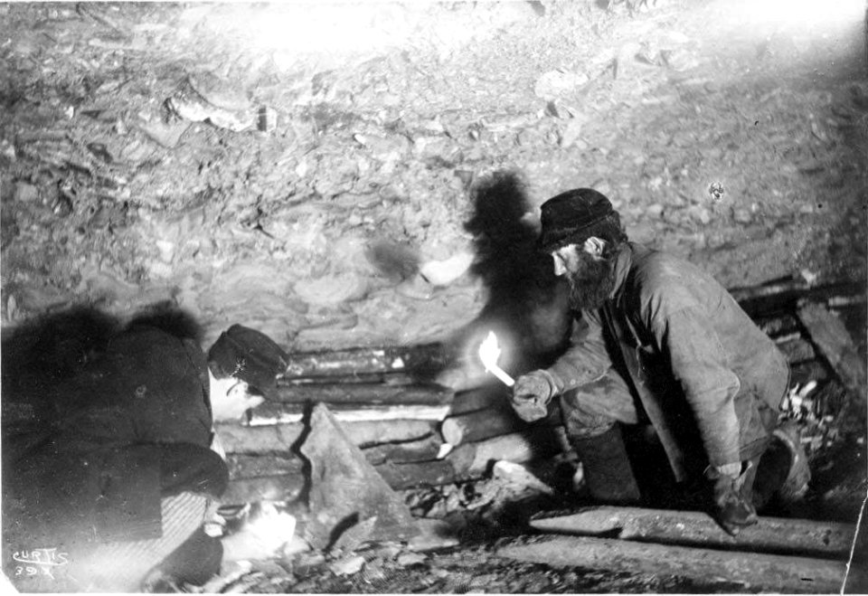 Two men, identified as Gorst and Ainsworth, building a fire in a mine shaft to thaw the frozen ground, Yukon Territory, ca 1898 (CURTIS 1829)