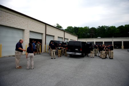 Two groups of law enforcement explorers stand around a vehicle photo